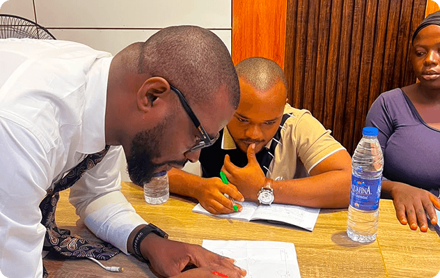 Instructor guiding students through design drawings at a table